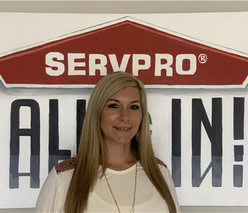 Female employee Lacee Lambert posing for a photo in front of a SERVPRO poster.